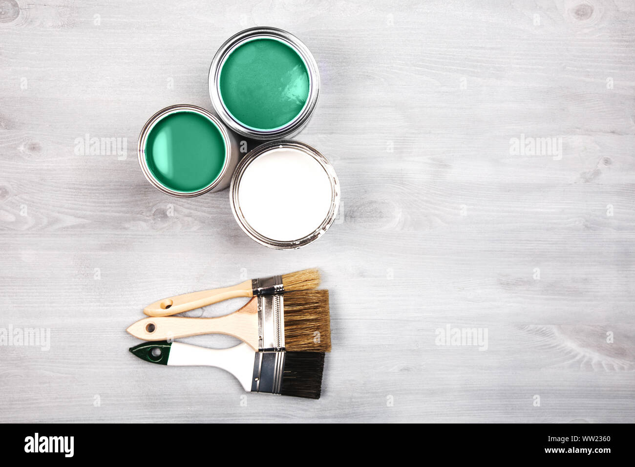 Green paint cans and colored brushes on white wooden background Stock Photo