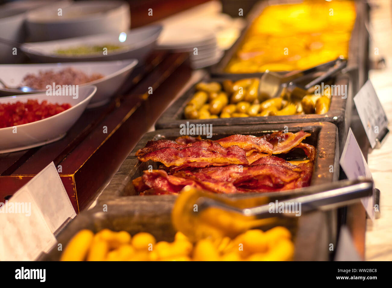 Buffet breakfast at a Chinese hotel. Closeup bacon on blurry background of food trays. Breakfast is included in the hotel. Stock Photo