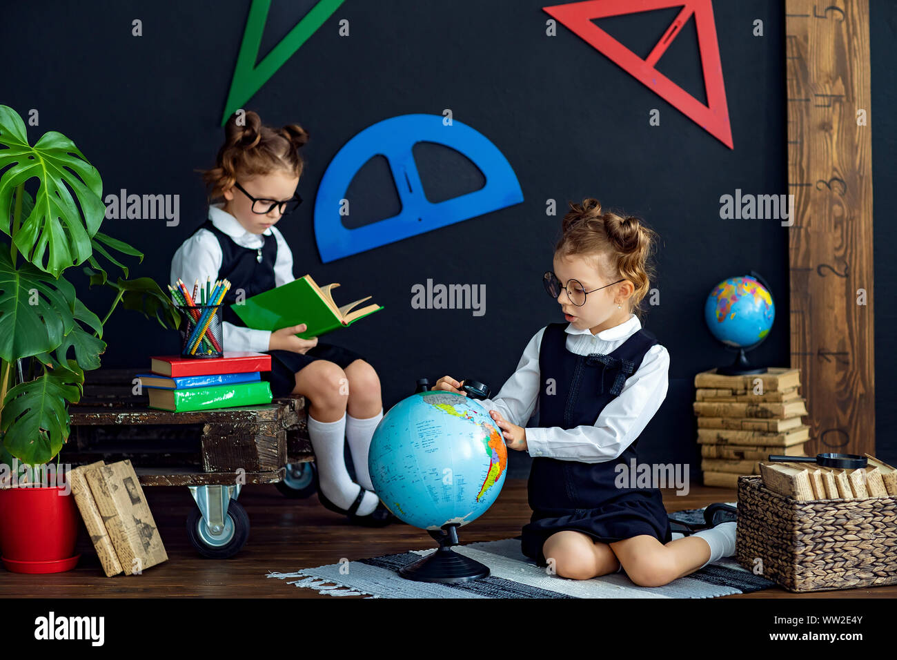 Little twins in school uniform and glasses reading interesting books ...