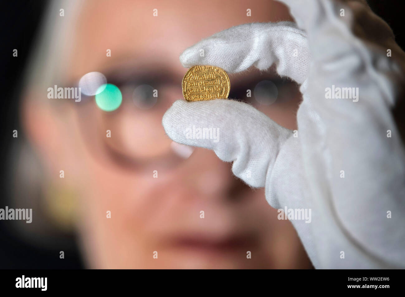 A member of staff at Morton & Eden holds an extremely rare early Islamic gold coin which is expected to fetch £1.4m at auction in London. PA Photo. Picture date: Thursday September 12, 2019. Measuring a 20mm across, about the size of a modern £1 piece, it is one of the world's rarest and most treasured Islamic gold coins from the first dynasty of Islam, the Umayyad gold dinar dated 105h (723AD). Photo credit should read: Victoria Jones/PA Wire Stock Photo