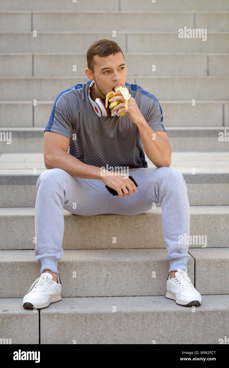 Eating banana fruit runner young man portrait format sports training fitness outdoor Stock Photo