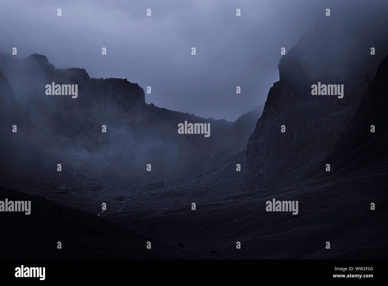 Fog in rocky mountain valley.Dark and dramatic landscape scene with atmospheric mood in English Lake District.Mountain pass.High up.Bad weather.Gloomy. Stock Photo