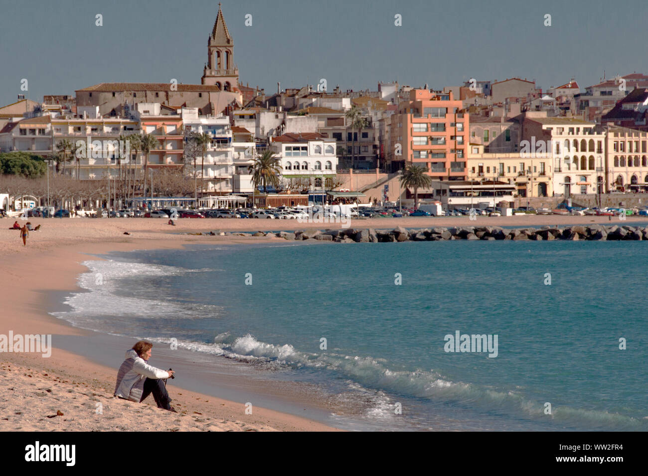 A woman sits contemplating on the beach of Palamos, Catalunya, Spain Stock Photo