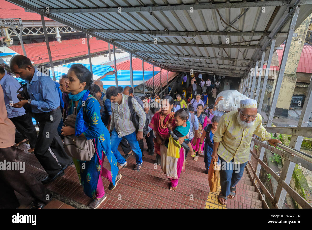 Passengers of local trains at Byculla Station in Mumbai, India, crossing over a bridge across the rail platforms Stock Photo
