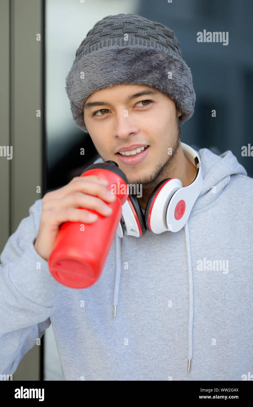 Smiling young latin man drinking water portrait format winter sports training fitness outdoor Stock Photo