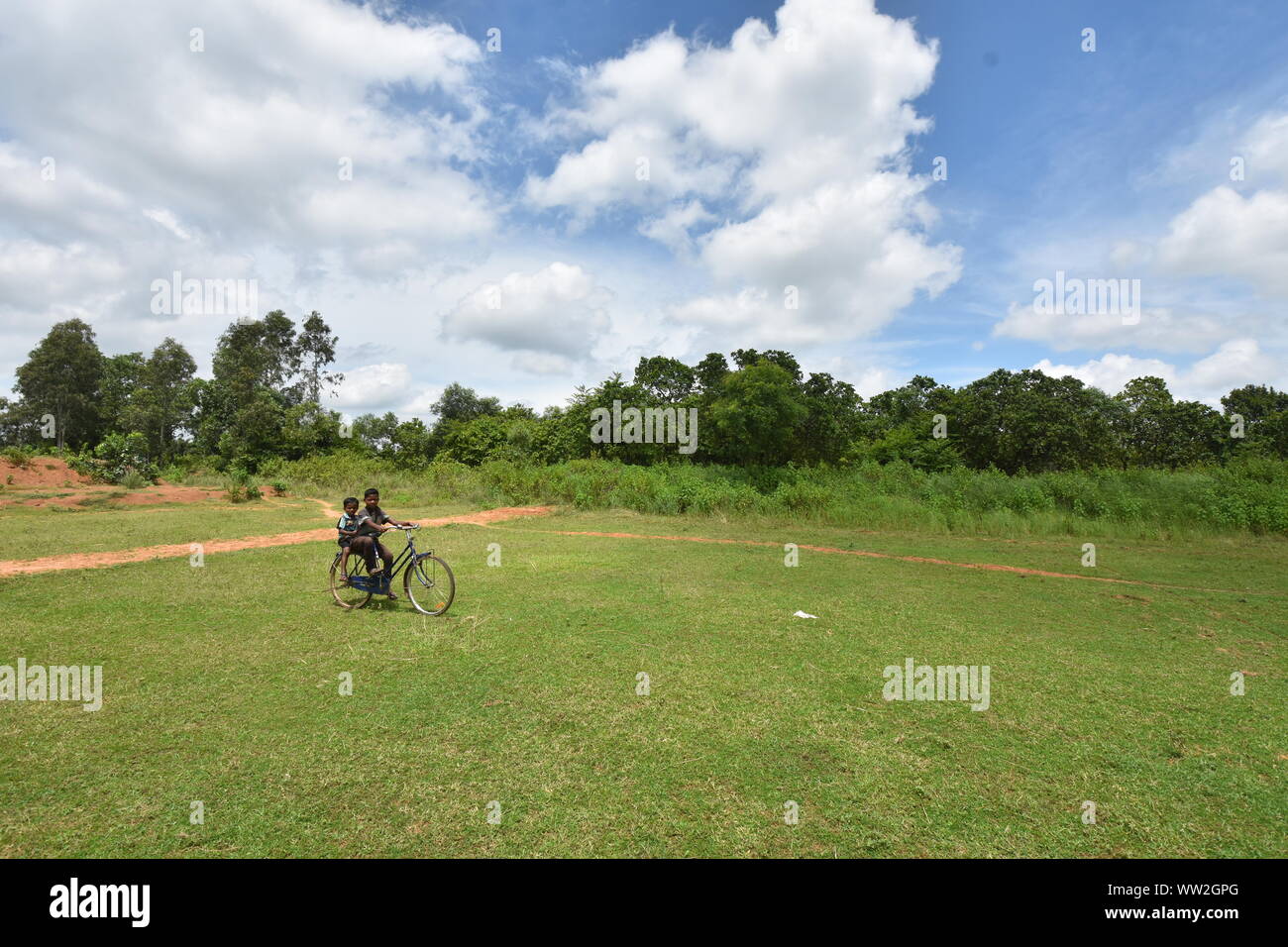 Kids cycling over a field. Village Banstala, Jhargram, West 