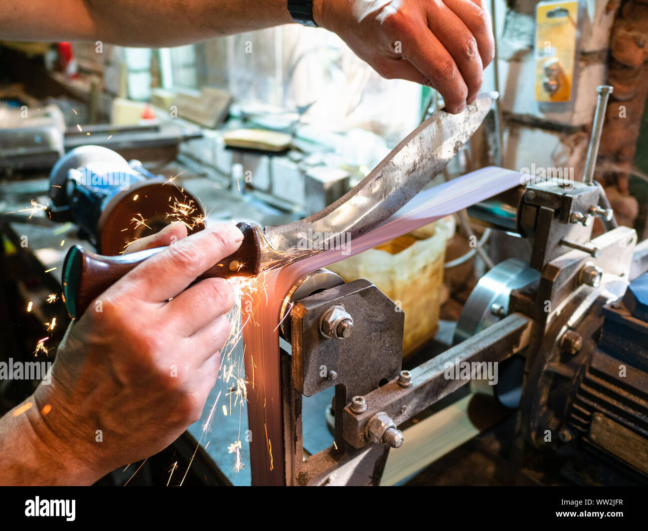 sharpening Khukur traditional Nepali knife on grinding machine in rural workshop Stock Photo