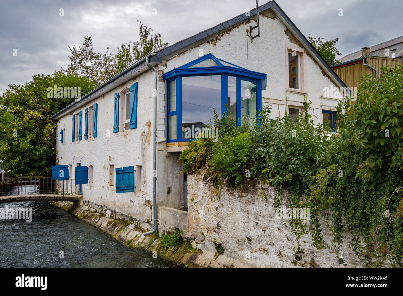 Old house along the river of tone with blue shutters in the city of Virton in the province of Luxembourg in Belgium Stock Photo
