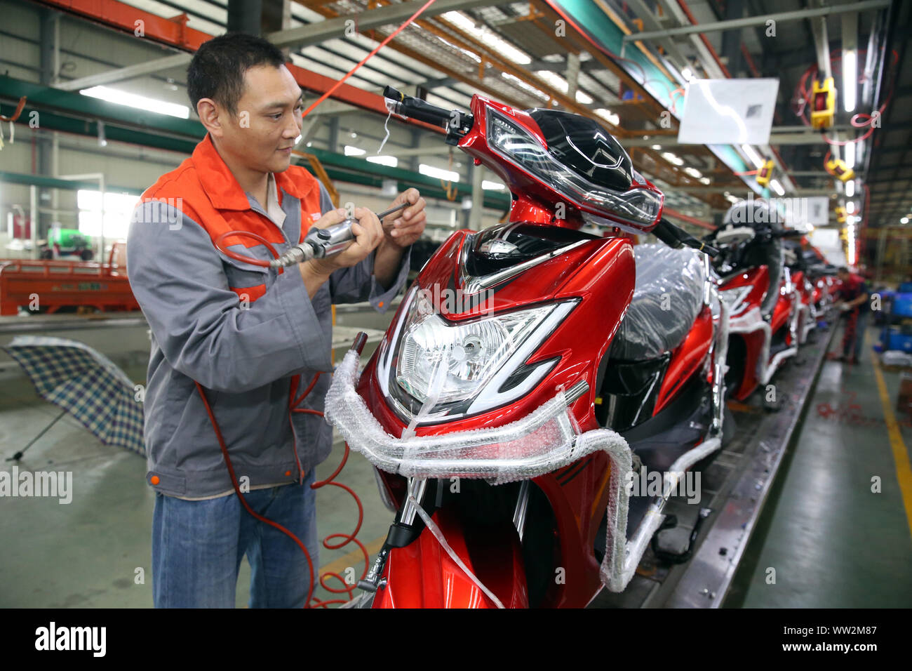 A Chinese factory worker assembles electric bikes on the assembly line at the plant of Sichuan BGB Electric Vehicle Co., Ltd. in Emei City, southwest Stock Photo
