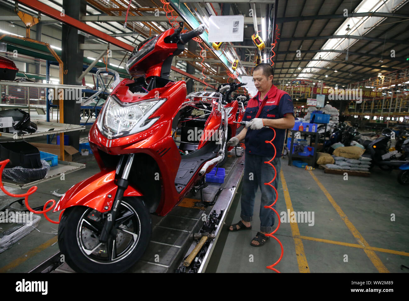 A Chinese factory worker assembles electric bikes on the assembly line at the plant of Sichuan BGB Electric Vehicle Co., Ltd. in Emei City, southwest Stock Photo