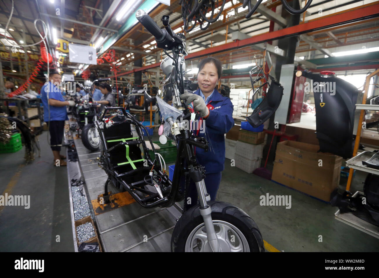 Chinese factory workers assemble electric bikes on the assembly line at the plant of Sichuan BGB Electric Vehicle Co., Ltd. in Emei City, southwest Ch Stock Photo