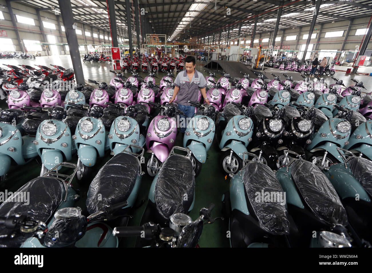 A Chinese factory worker lines up newly-manufactured electric bikes at the plant of Sichuan BGB Electric Vehicle Co., Ltd. in Emei City, southwest Chi Stock Photo