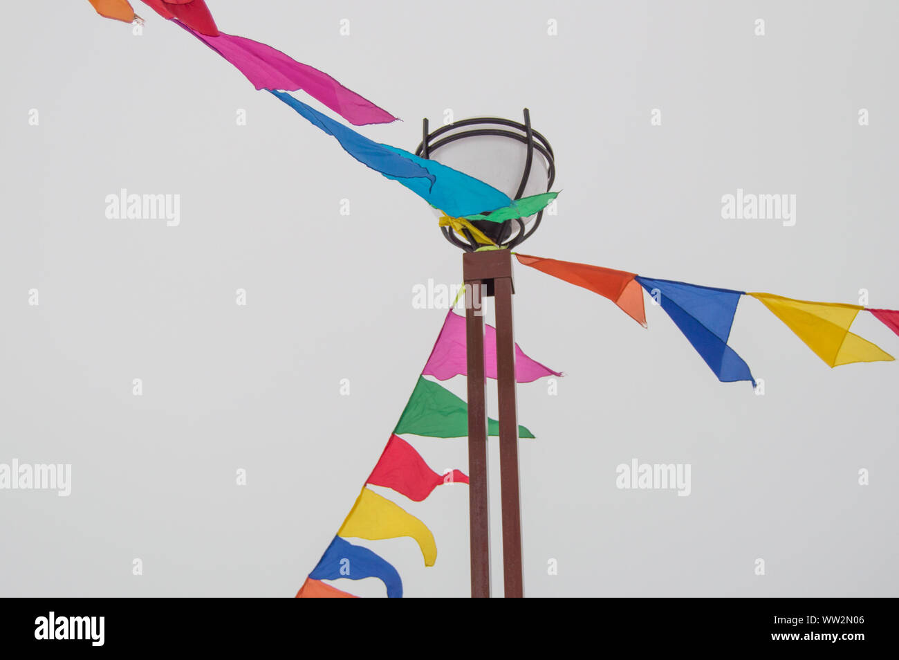 Colorful triangular cloth flags hanging on ropes tied to a lamppost ...