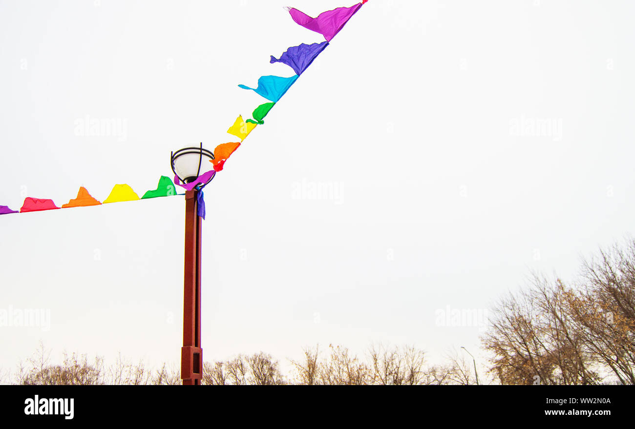 Colorful triangular cloth flags hanging on ropes tied to a lamppost ...