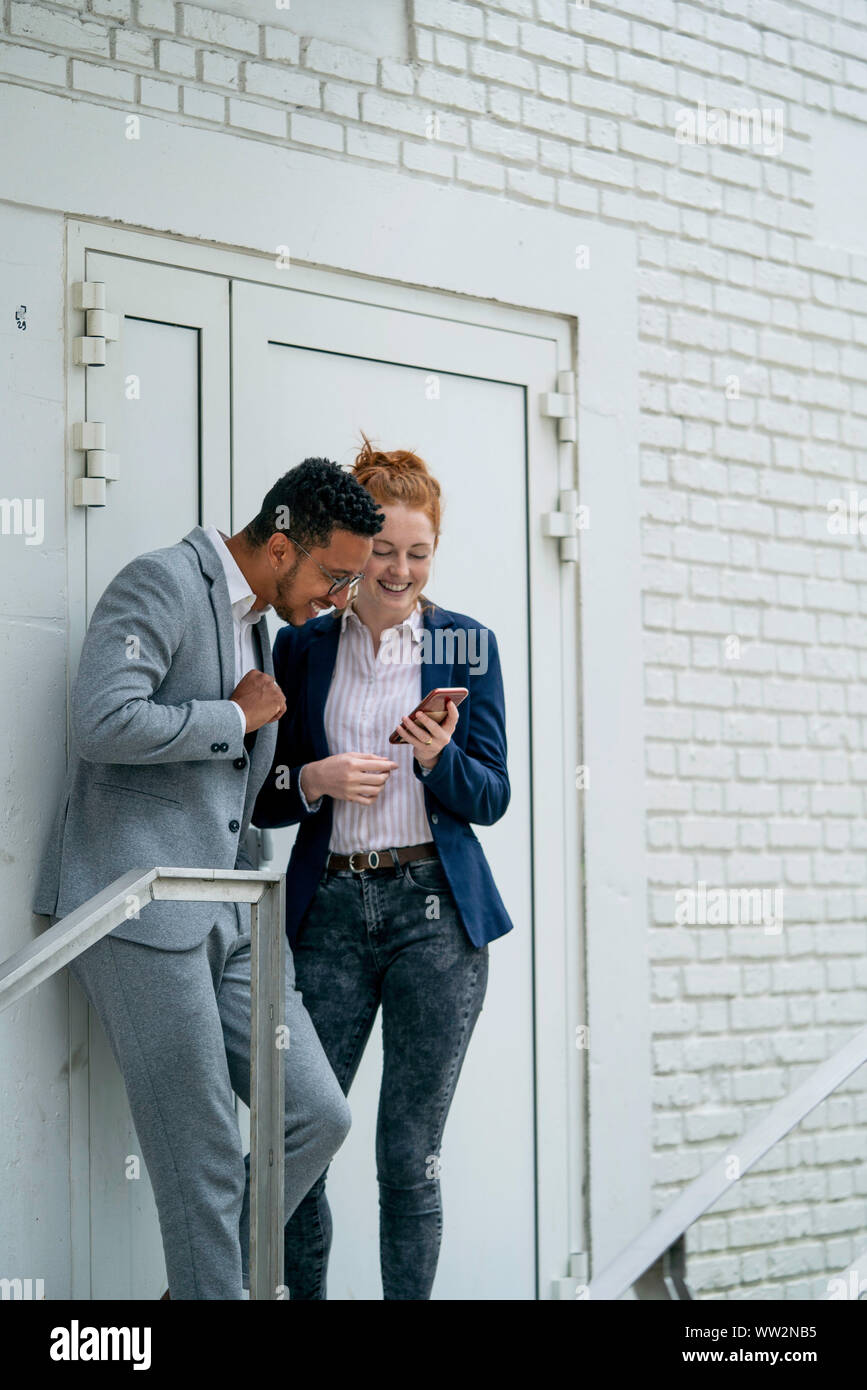 Couple using smart phone outdoors Stock Photo
