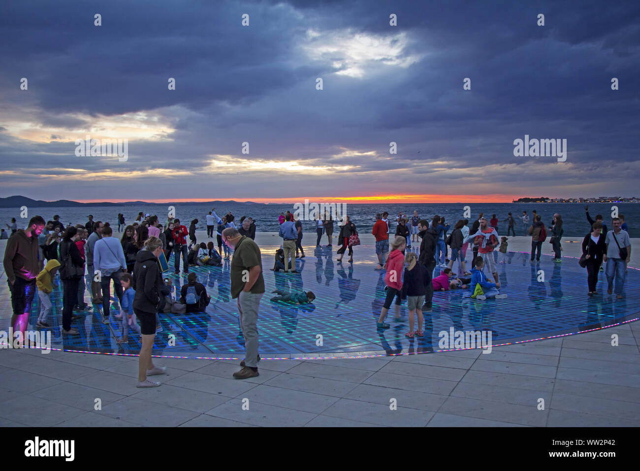 ZADAR/CROATIA - JULY 16: Many people watch sunset over Adriatic sea on famous solar panel urban installation 'Greeting to the Sun', July 16, 2016, in Stock Photo