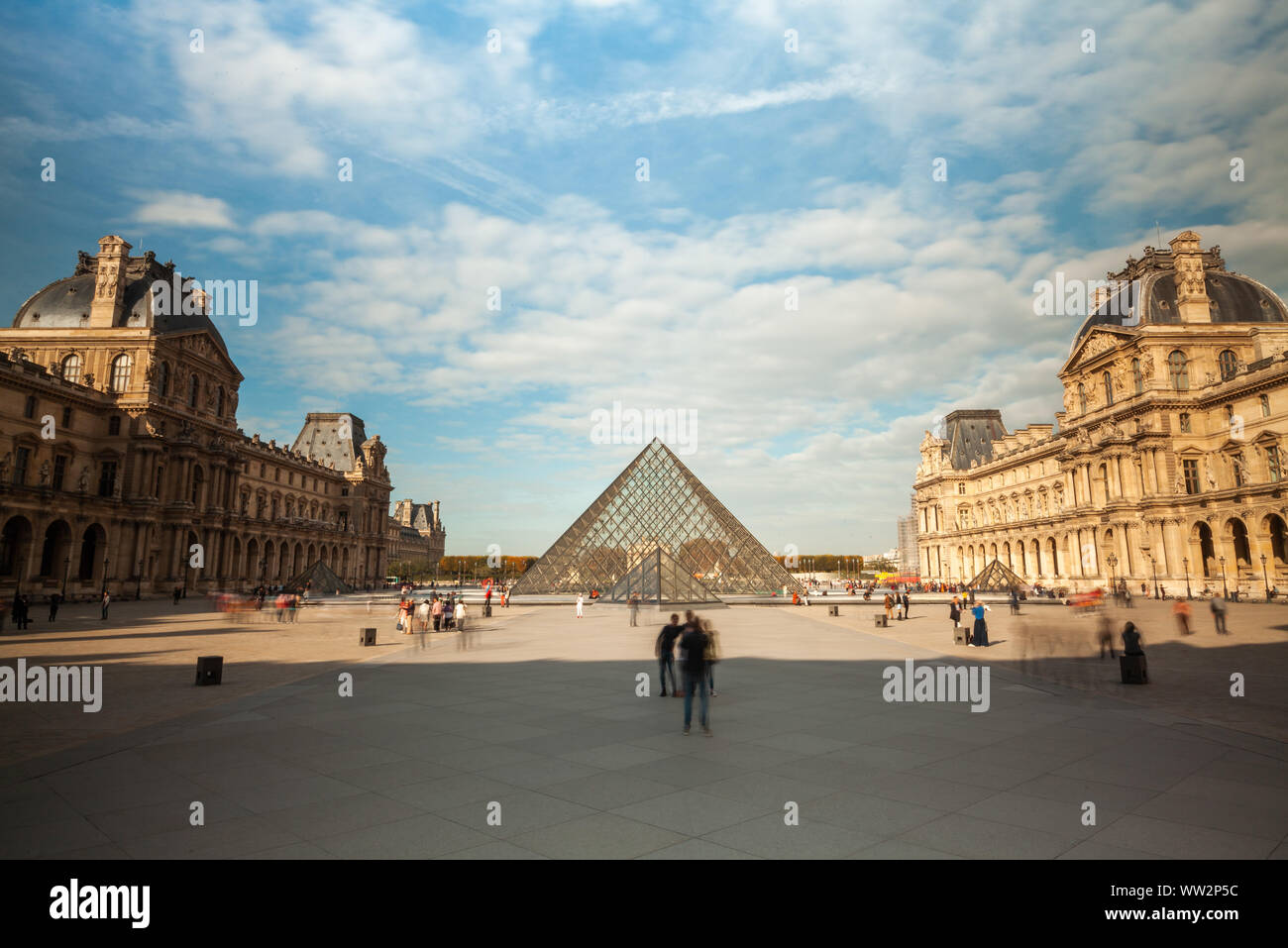 View of the Louvre Museum and the glass pyramid with tourists Stock Photo