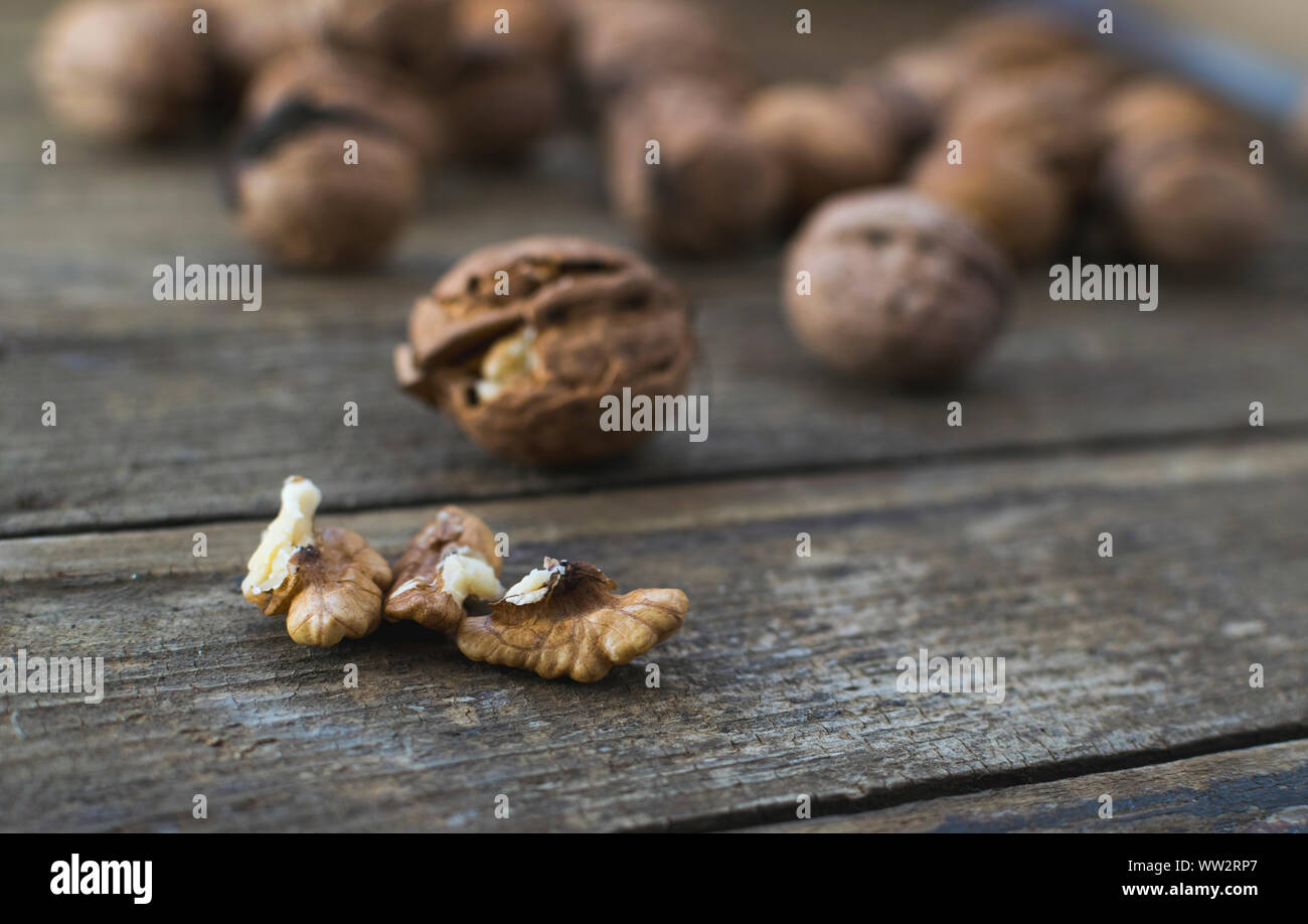 Whole and chopped walnuts on wooden table. Stock Photo