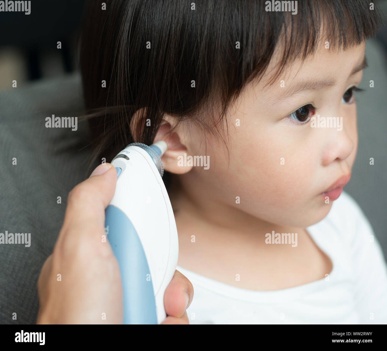 Mother checking temperature her daughter in the ear with ear