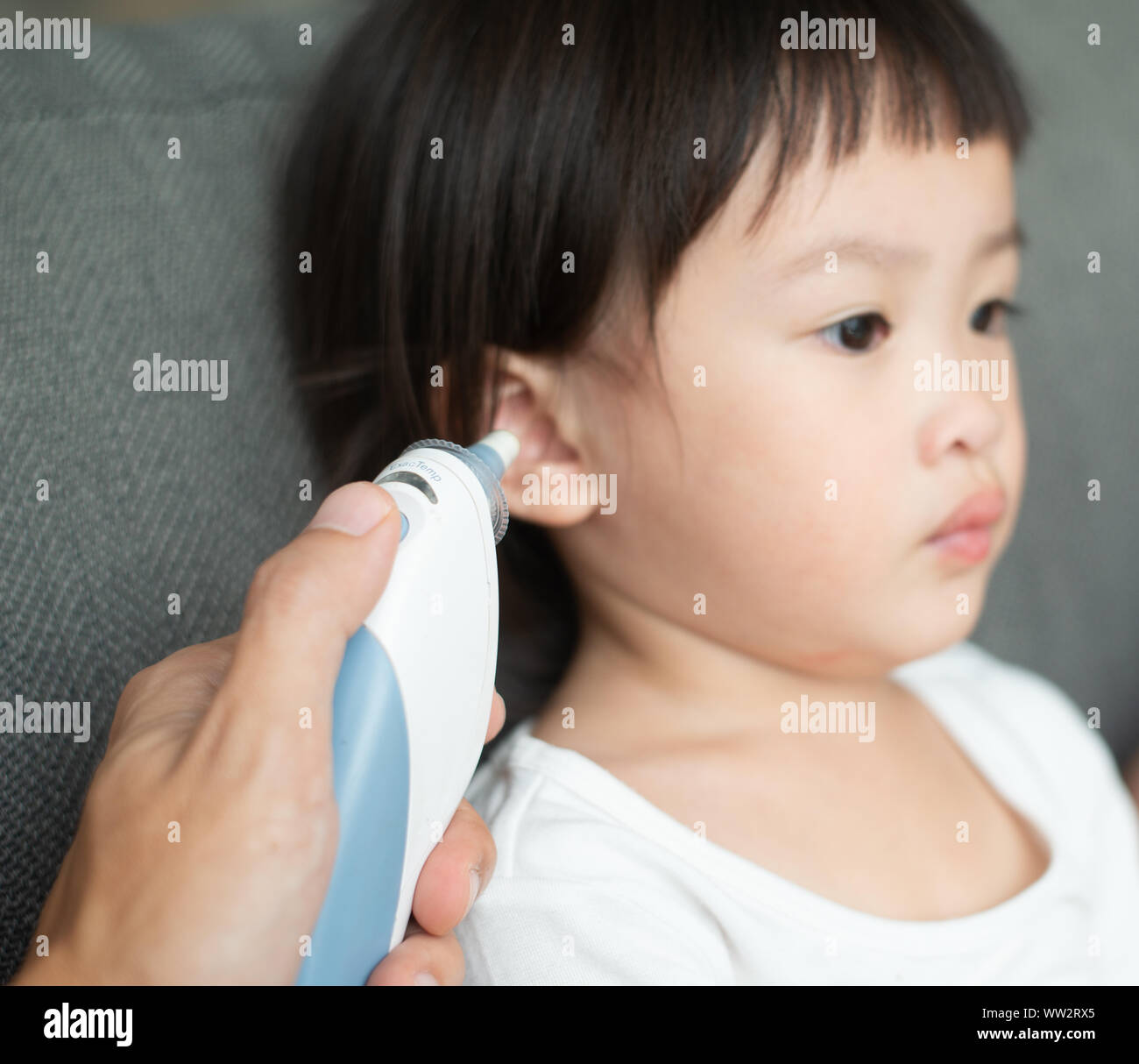 Mother checking temperature her daughter in the ear with ear