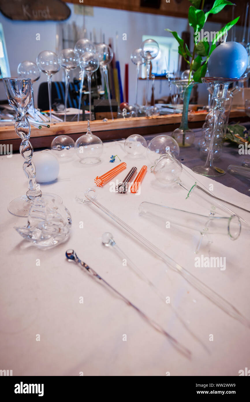 Finished and unfinished hand-blown glass balls on the table of a glassblower manufactory. Stock Photo