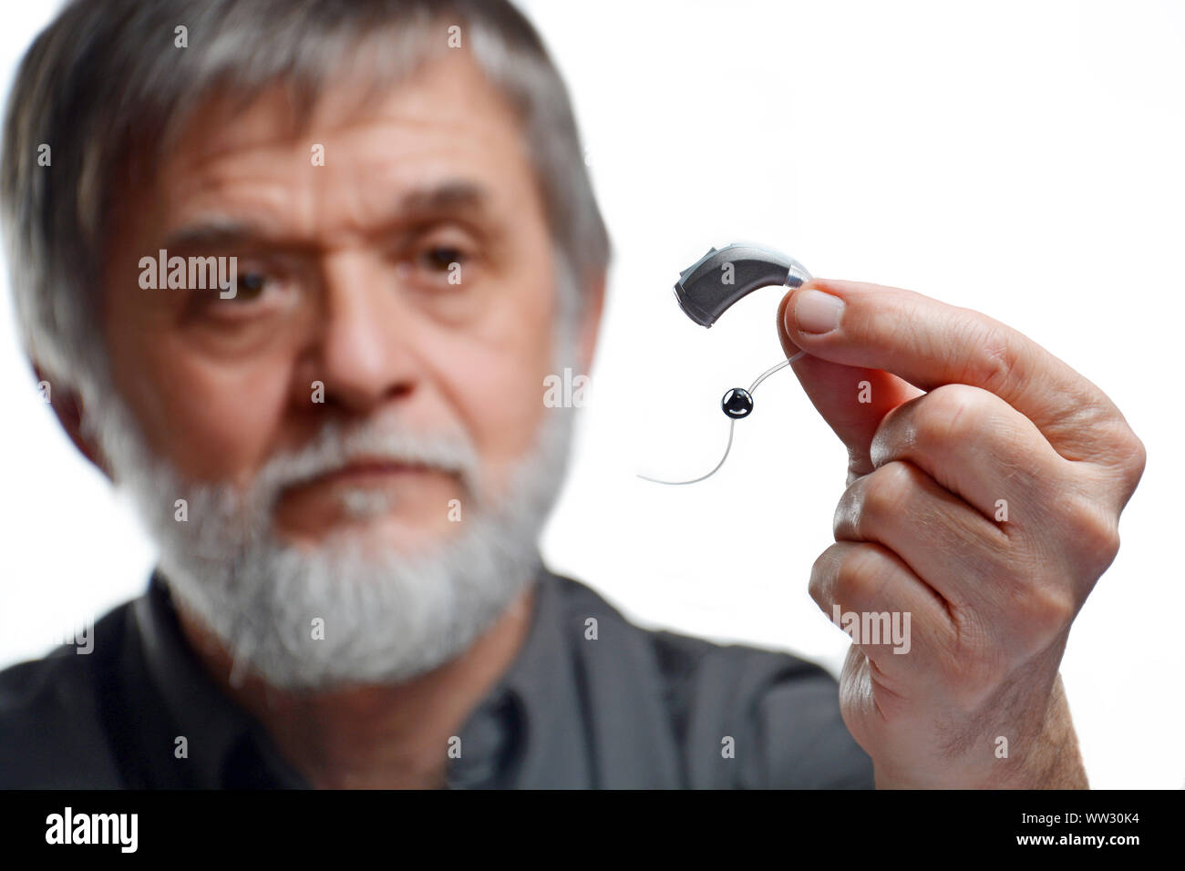 Old man looks exactly at hearing aid Stock Photo