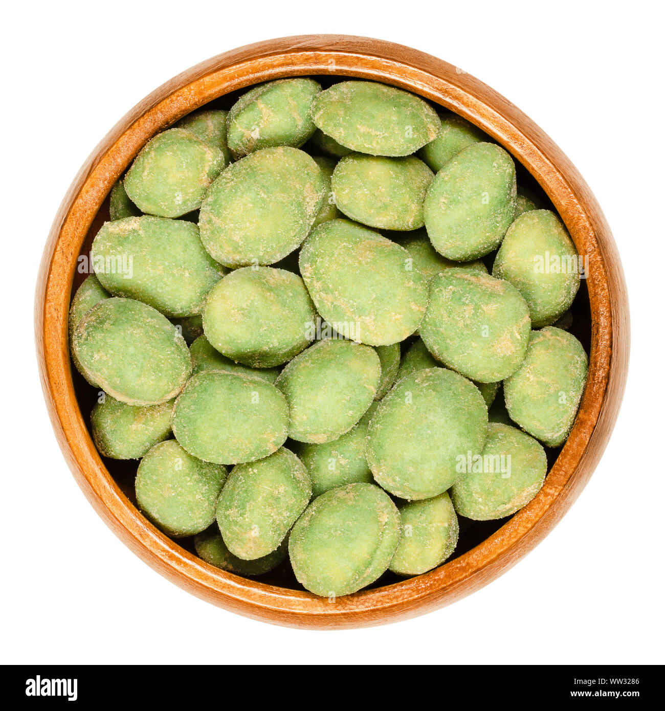 Wasabi peanuts in wooden bowl on white background. Green colored spicy nut snack. Peanuts in rice dough, coated with super hot wasabi powder. Stock Photo