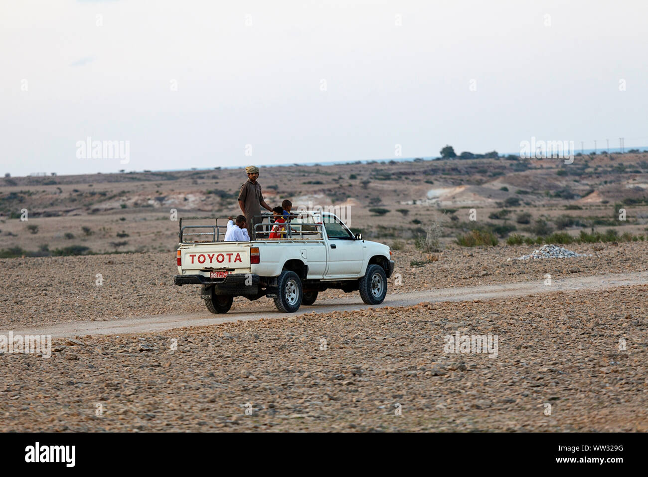 Local men and children driving in a pickup truck in dry Omani landscape, oman Stock Photo