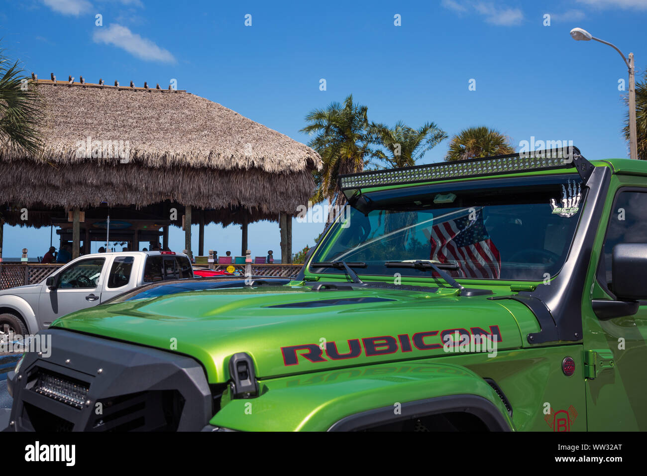 Stars and Stripes American flag reflected in the windscreen of a bright green Jeep Wrangler Rubicon, Hudson beach, Florida Stock Photo
