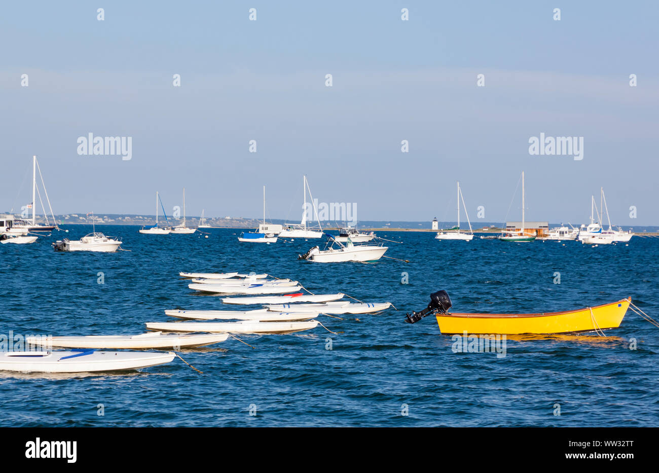 Yellow dinghy standing out from moored Sunfish sailboats in Cape Cod Bay. Stock Photo