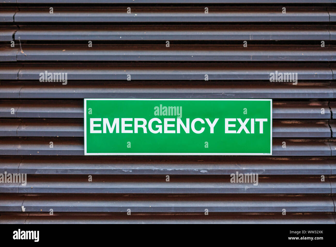 Green Sign Emergency Exit at Building Door Stock Photo