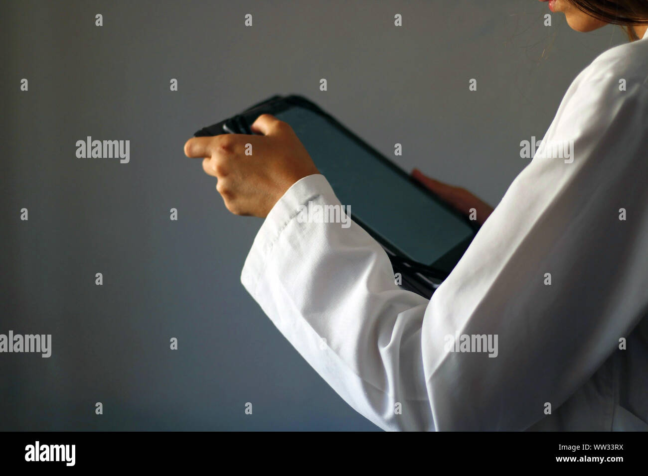 Medicine Concept: Young female doctor on a gray background using a digital tablet. Healthcare technology. Stock Photo