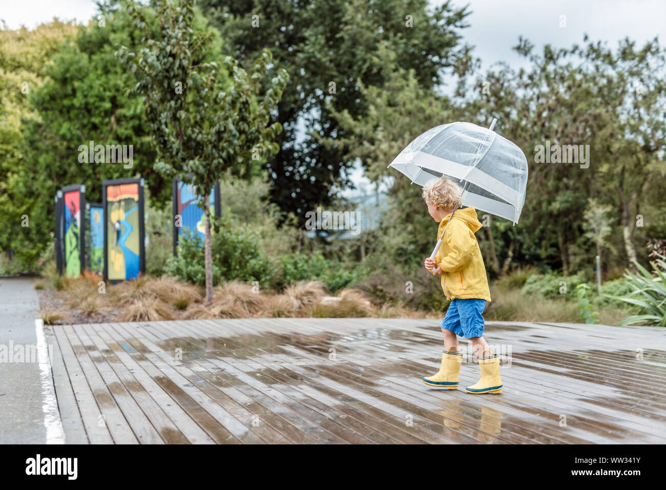 Child wearing rain boots and holding umbrella Stock Photo
