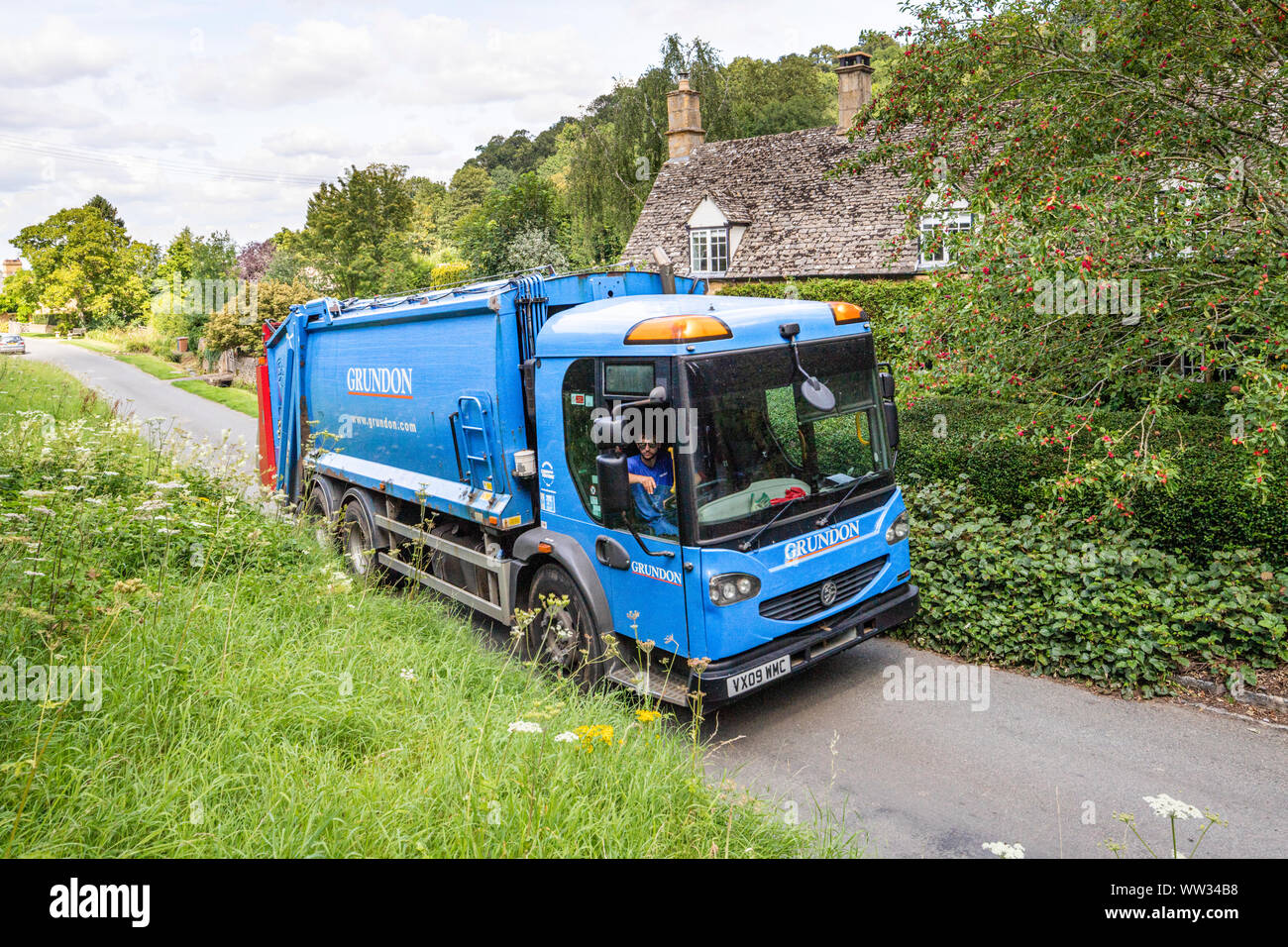 Grundon Waste Management dustbin lorry in a narrow lane in the Cotswold village of Buckland, Gloucestershire UK Stock Photo