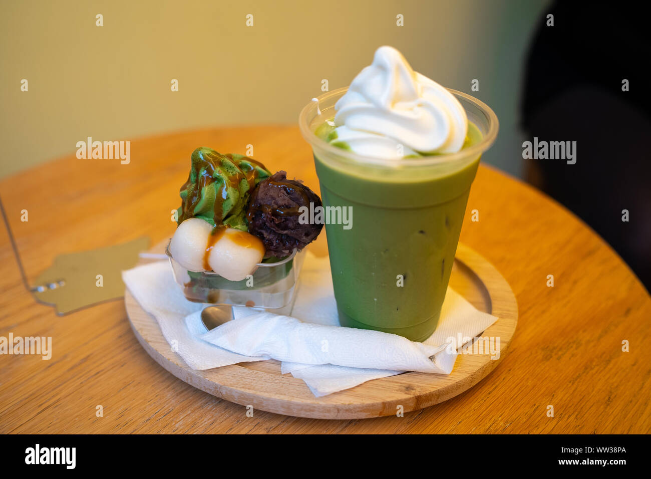 Cup of iced Matcha Grean Tea Latte with cream and bowl of  Matcha ice cream with Azuki Bean Paste and Mochi with black sugar sirup Stock Photo