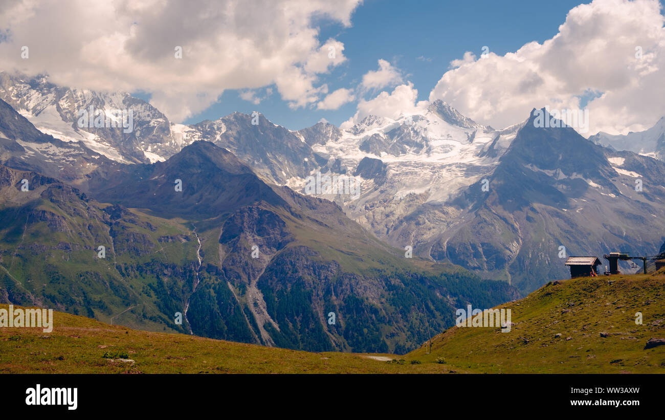 Spectacular view on high snowy peaks of the Pennine Alps (Besso, Zinalrothorn) under cloudy sky seen from Sorebois in the summer. Zinal, Val d' Annivi Stock Photo