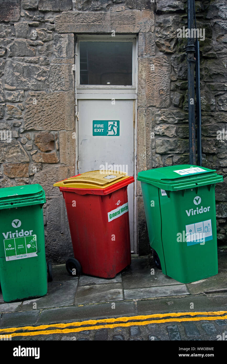 Wheelie bins in an alley with one blocking a fire escape. Stock Photo