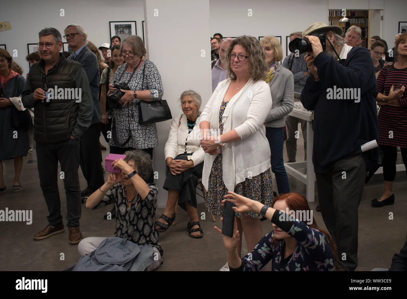 Marketa Luskacova photographer (sitting hands on knees) at a party for her exhibition at the MPF  Martin Parr Foundation Bristol UK 2019, 2010s, HOMER SYKES Stock Photo