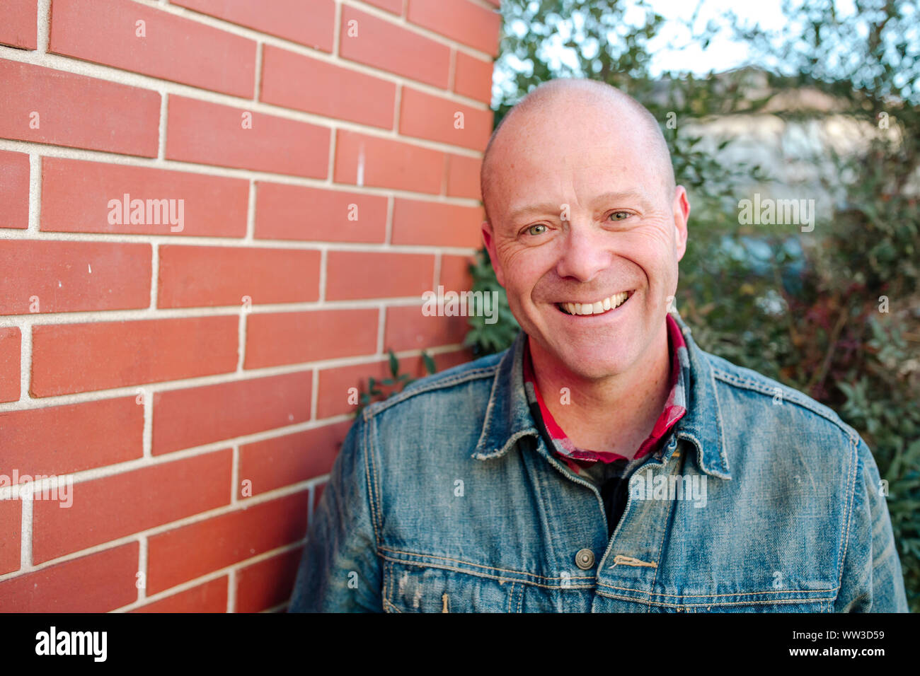 Portrait of smiling man in front of brick wall sunny day in California Stock Photo