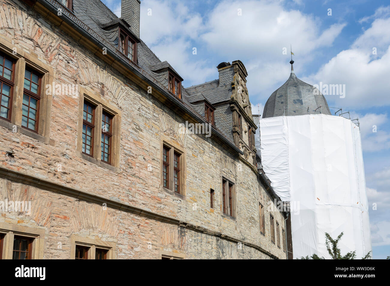 Brick wall of the Wewelburg castle with in the background a tower in scaffolds and wrapped for renovation Stock Photo