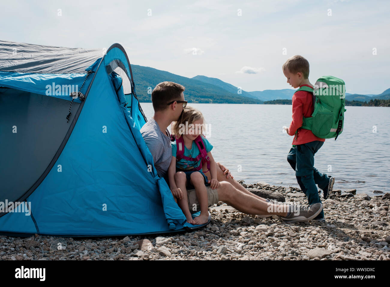 father sitting in a tent with his son and daughter camping by the sea Stock Photo
