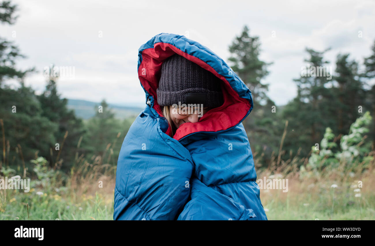 portrait of a woman wrapped up in a sleeping bag wild camping outdoors