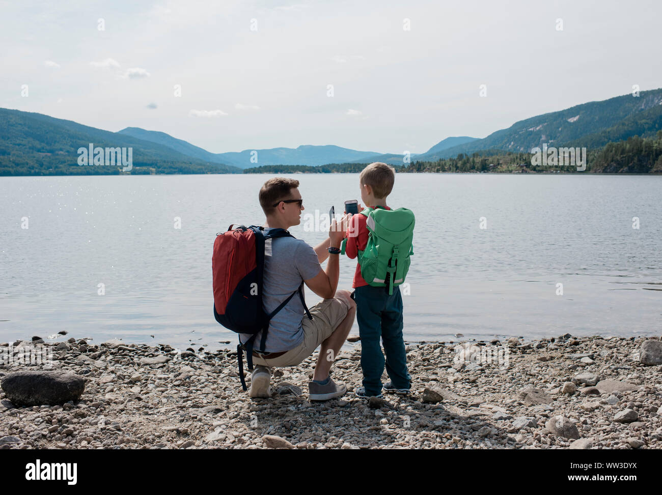 father and son taking pictures with cell phones of the mountains Stock Photo