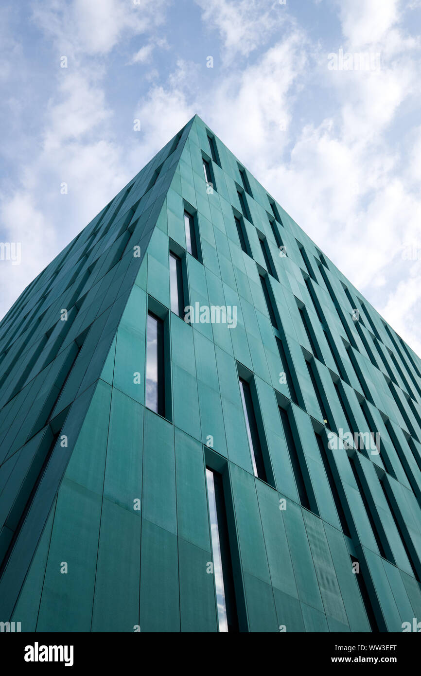Minimal View from bottom of generic green sky scraper looking at pointy corner into a cloudscape Stock Photo