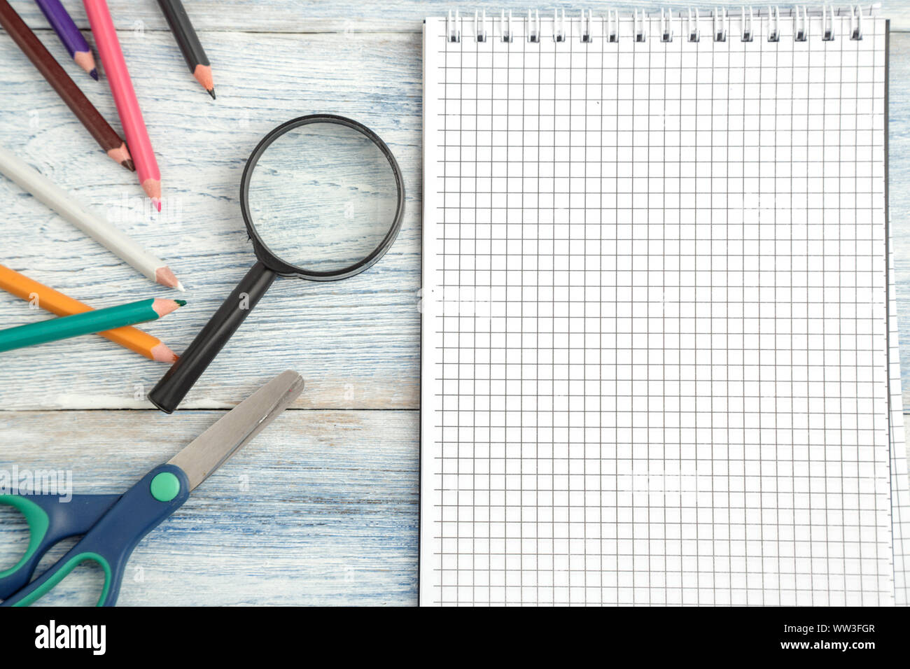 stationery, a paper notebook and a magnifying glass on a light blue old ...
