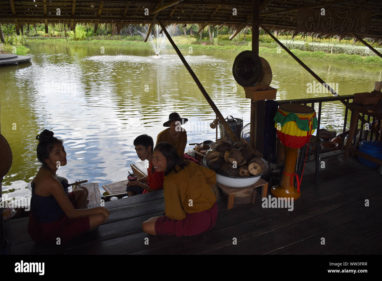 Kanchanaburi, Thailand, 09.09.2019: Local Thai people in traditional Thai, Siamese dresses are resting and eating on the lake on a floating house in t Stock Photo