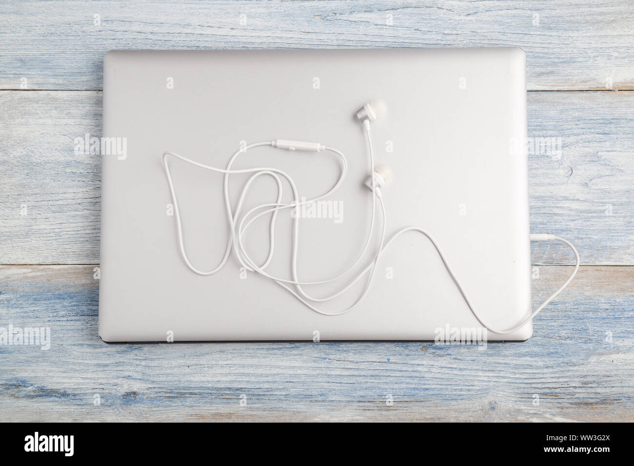 gray laptop with white headphones on a light blue old wooden background ...