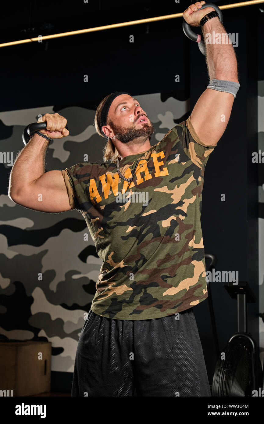 Muscular man in a sports uniform stands on in the gym raising his hands ...