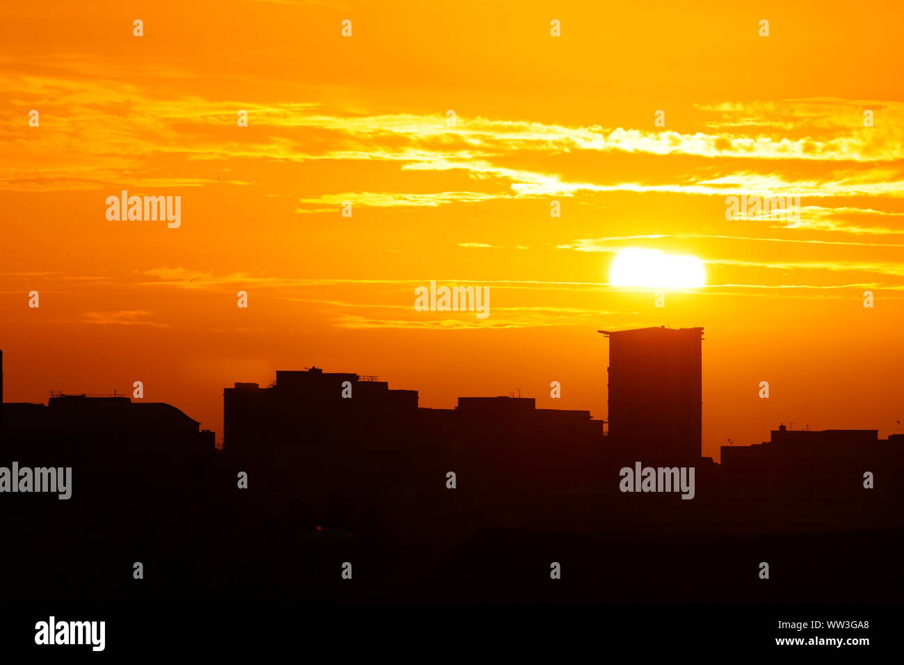 The sun rising behind a building in Leeds City Centre Stock Photo - Alamy