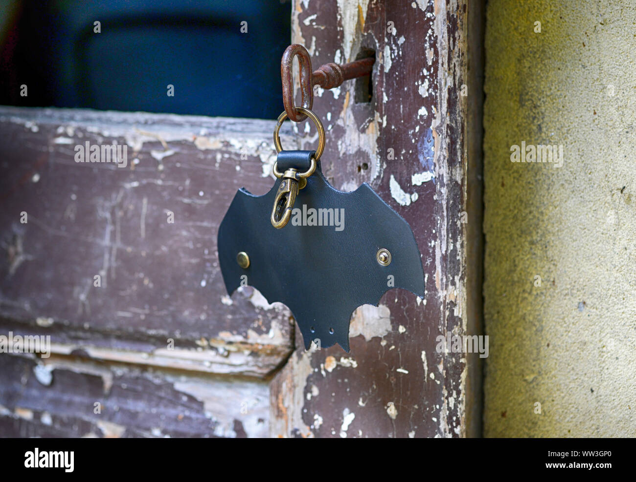Leather keychain in Bat shape and old key in wooden door. - image Stock Photo